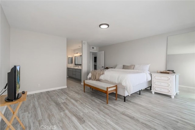 bedroom with ensuite bathroom and light hardwood / wood-style floors