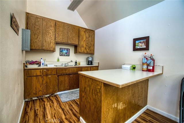 kitchen with kitchen peninsula, sink, dark hardwood / wood-style floors, and vaulted ceiling