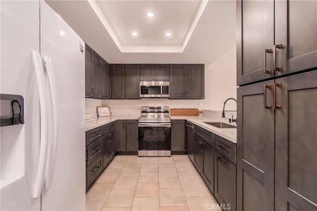 kitchen featuring dark brown cabinetry, sink, a raised ceiling, light tile patterned floors, and appliances with stainless steel finishes