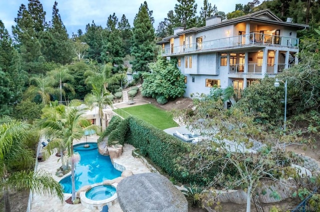 exterior space featuring a swimming pool with hot tub and a balcony