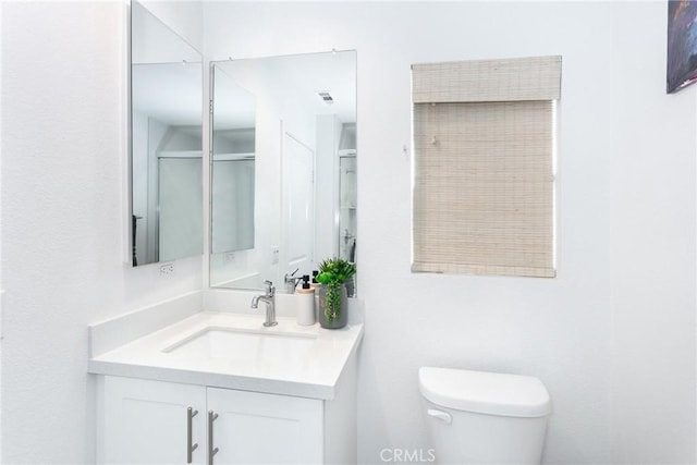 bathroom featuring vanity, toilet, and a shower with door