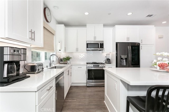 kitchen with backsplash, white cabinets, sink, dark hardwood / wood-style floors, and appliances with stainless steel finishes