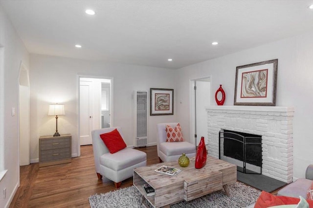 living room with wood-type flooring and a stone fireplace