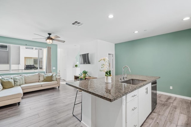 kitchen with sink, white cabinets, a center island with sink, stainless steel dishwasher, and light wood-type flooring