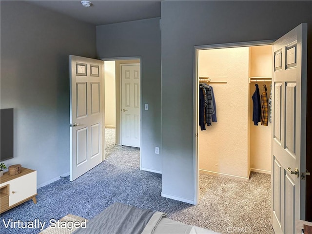 unfurnished bedroom featuring a walk in closet, a closet, and carpet