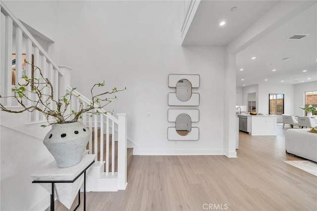 foyer entrance with light hardwood / wood-style floors and sink