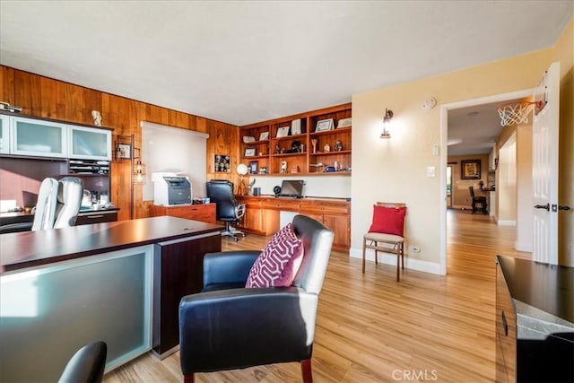 office area featuring wood walls, light hardwood / wood-style flooring, and built in desk