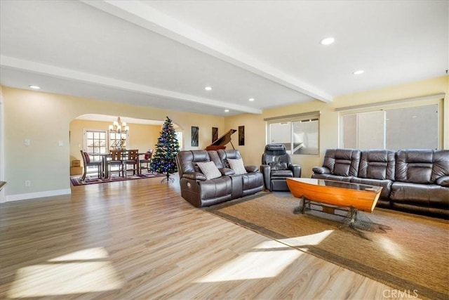 living room with beam ceiling, light wood-type flooring, and an inviting chandelier