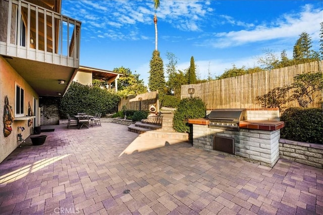 view of patio / terrace featuring a grill, a balcony, and exterior kitchen