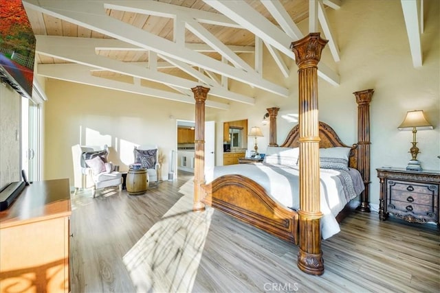 bedroom featuring hardwood / wood-style floors, beamed ceiling, high vaulted ceiling, and decorative columns