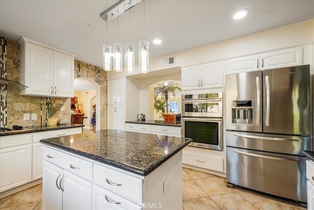 kitchen featuring dark stone countertops, white cabinetry, a center island, and appliances with stainless steel finishes