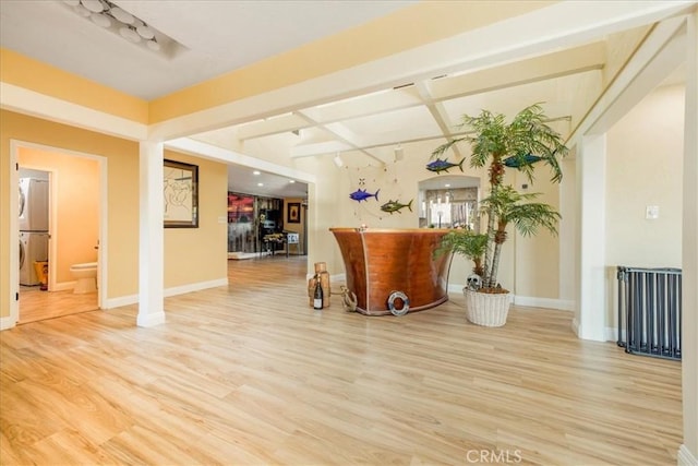 interior space with hardwood / wood-style floors, rail lighting, and stacked washer and clothes dryer