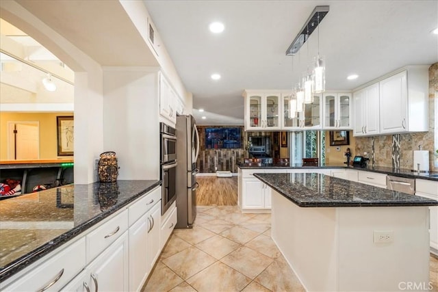 kitchen featuring dark stone counters, white cabinetry, a kitchen island, and hanging light fixtures