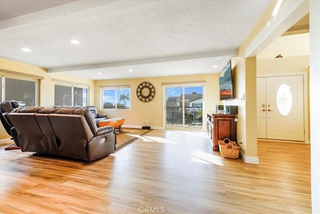 living room featuring beamed ceiling and light hardwood / wood-style flooring