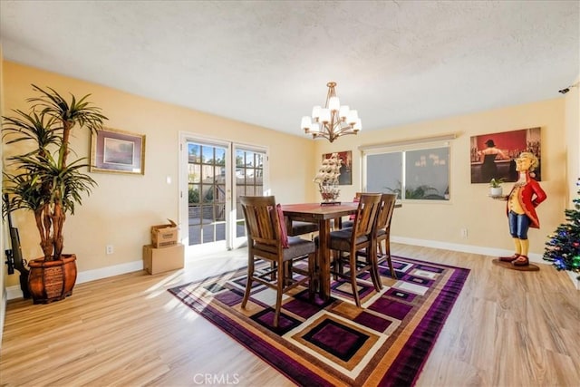 dining area featuring light hardwood / wood-style floors, a textured ceiling, and a notable chandelier