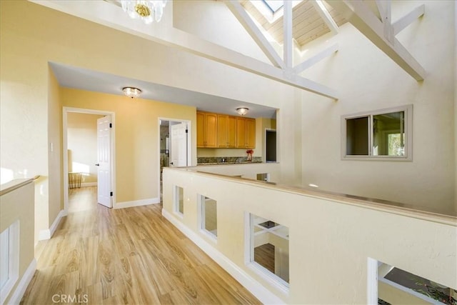 kitchen featuring light wood-type flooring, a skylight, and high vaulted ceiling