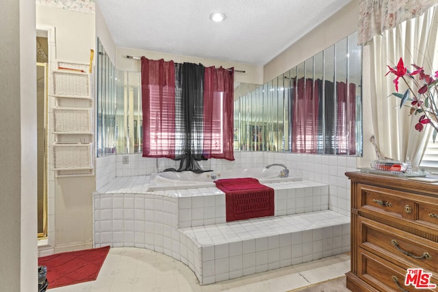 bathroom with tiled tub and a textured ceiling