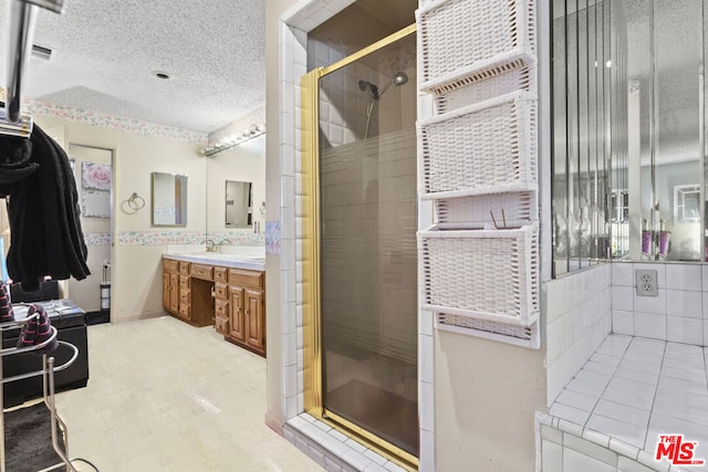 bathroom featuring a shower with door, vanity, and a textured ceiling