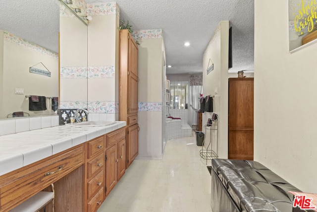 bathroom featuring vanity, a textured ceiling, and tile walls