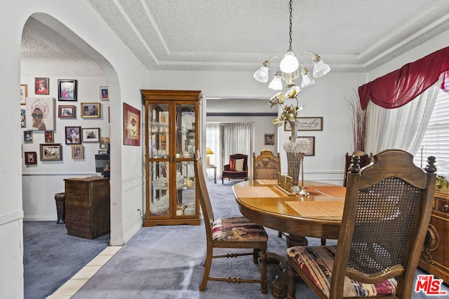 carpeted dining room featuring a notable chandelier and a textured ceiling