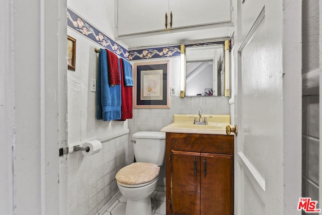 bathroom featuring tile patterned flooring, vanity, tile walls, and toilet