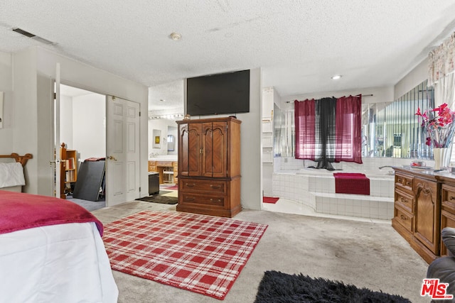 carpeted bedroom featuring a textured ceiling and ensuite bathroom