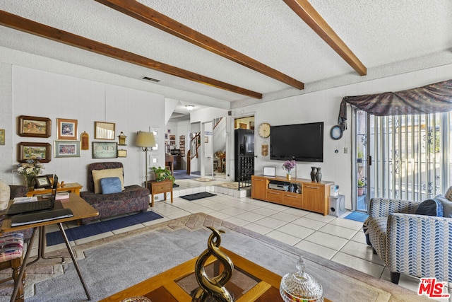 living room with beamed ceiling, light tile patterned floors, and a textured ceiling