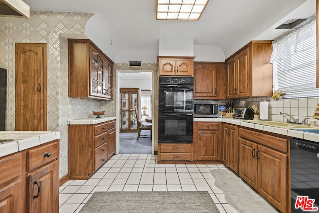 kitchen with tile countertops, black appliances, sink, decorative backsplash, and light tile patterned floors