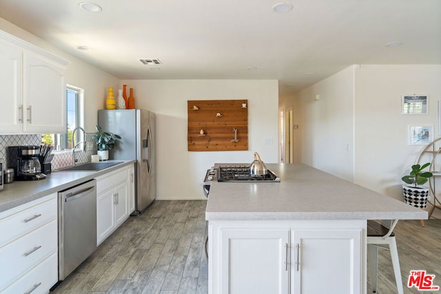 kitchen featuring sink, white cabinets, light hardwood / wood-style flooring, and appliances with stainless steel finishes