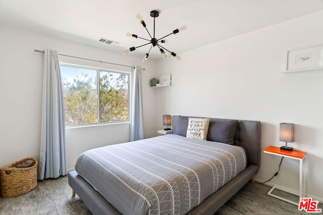 bedroom with dark wood-type flooring and an inviting chandelier