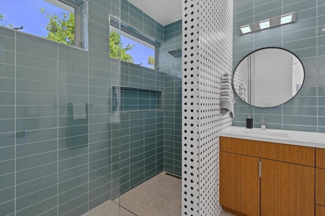 bathroom featuring backsplash, vanity, a tile shower, and tile walls