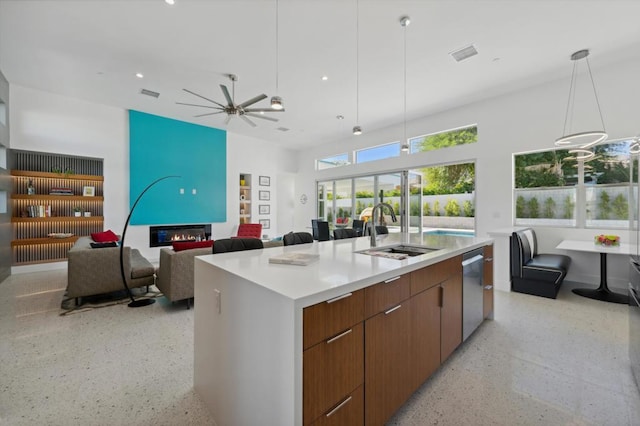 kitchen with stainless steel dishwasher, ceiling fan, sink, pendant lighting, and an island with sink