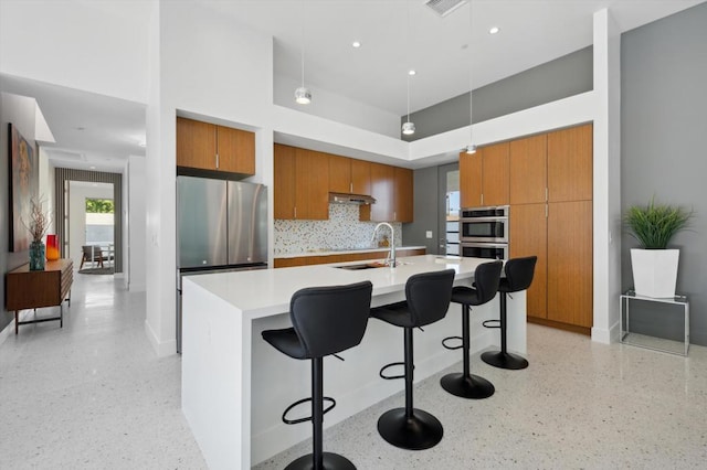 kitchen with a breakfast bar, sink, decorative light fixtures, tasteful backsplash, and a large island