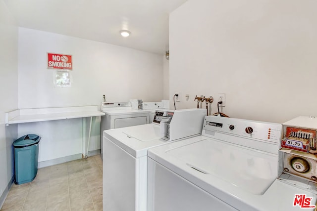 clothes washing area with washer and dryer and light tile patterned floors