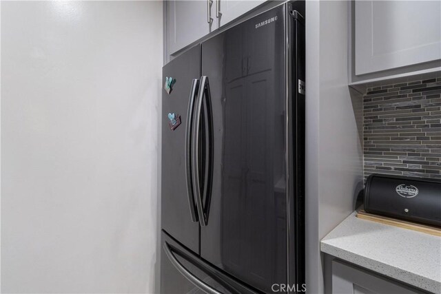 interior space with decorative backsplash and stainless steel refrigerator