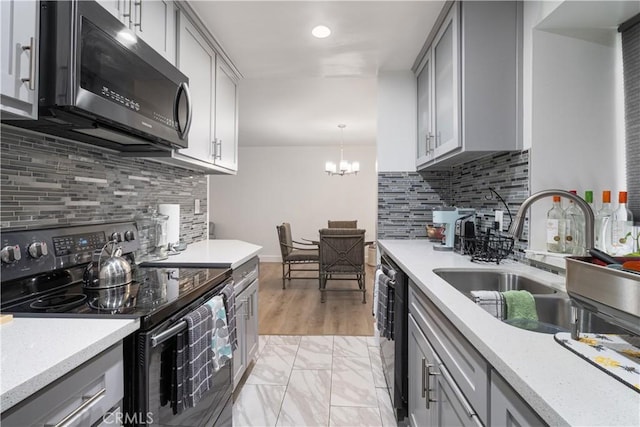 kitchen featuring decorative light fixtures, sink, black appliances, and gray cabinetry