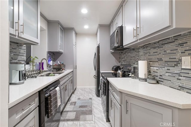 kitchen featuring appliances with stainless steel finishes, gray cabinetry, backsplash, and sink