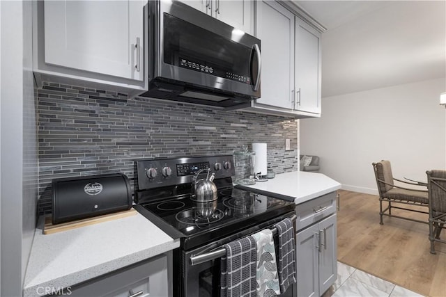 kitchen with backsplash, gray cabinetry, and stainless steel appliances