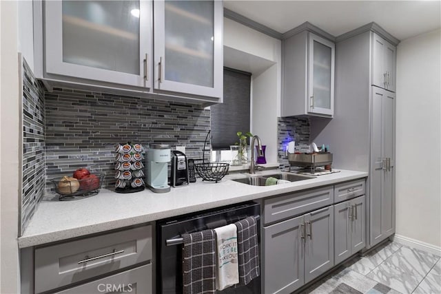 kitchen with gray cabinets, black dishwasher, backsplash, light stone counters, and sink