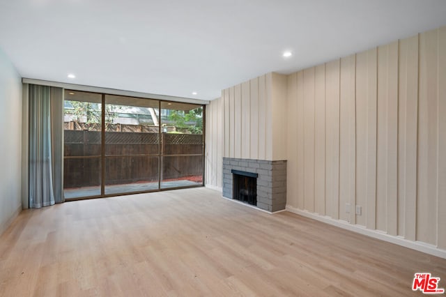 unfurnished living room featuring a fireplace, light wood-type flooring, and expansive windows