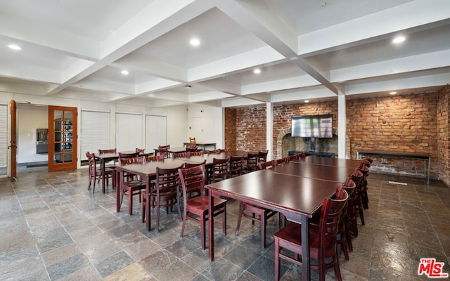 dining area with beamed ceiling, a fireplace, brick wall, and coffered ceiling