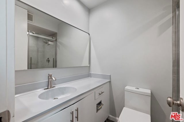 bathroom with a shower with door, vanity, and toilet