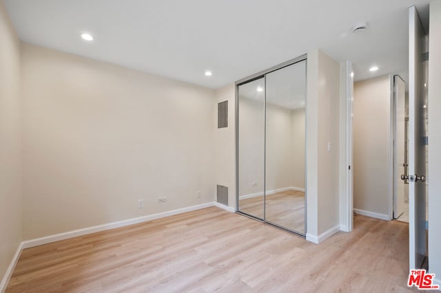 unfurnished bedroom with light wood-type flooring and a closet