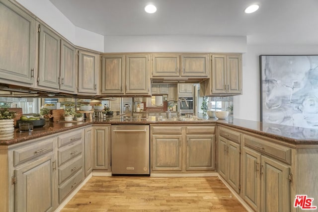 kitchen with sink, dishwasher, kitchen peninsula, dark stone countertops, and light wood-type flooring