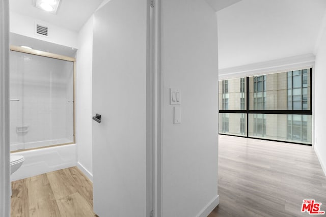 bathroom with toilet, bath / shower combo with glass door, and hardwood / wood-style flooring