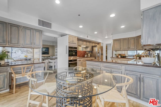 kitchen with decorative backsplash, appliances with stainless steel finishes, light hardwood / wood-style flooring, and sink