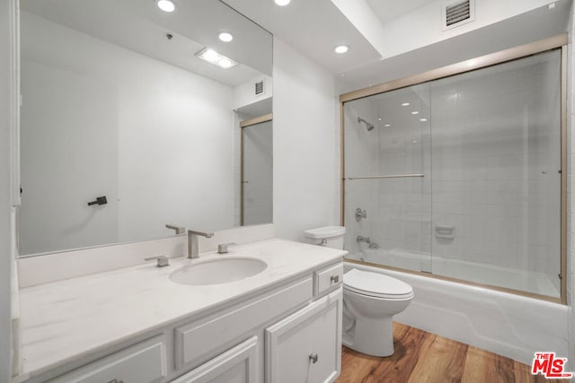 full bathroom featuring toilet, combined bath / shower with glass door, wood-type flooring, and vanity