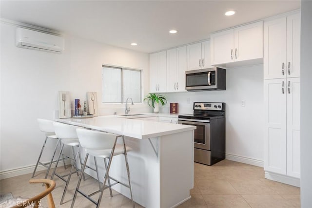 1809 W Bay Ave, Newport Beach, CA 92663 - kitchen featuring a kitchen bar, white cabinetry, kitchen peninsula, a wall unit AC, and stainless steel appliances