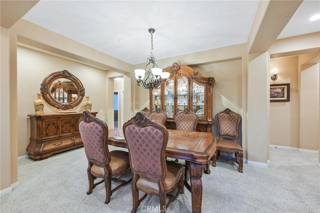 carpeted dining room with an inviting chandelier