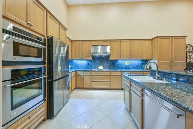 kitchen featuring sink, dark stone countertops, appliances with stainless steel finishes, tasteful backsplash, and light tile patterned flooring